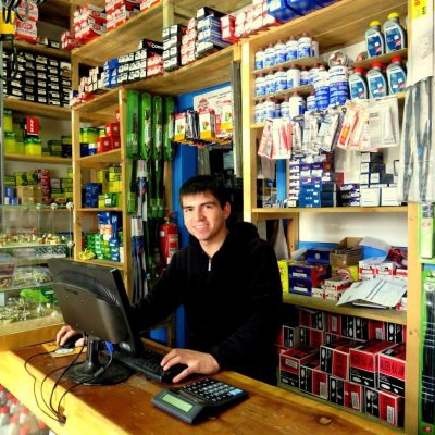 Vendedor atendiendo en mostrador rodeado de repuestos y aditivos automotrices en Repuestos Elgueta & Vásquez, Valdivia
